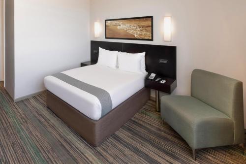 a hotel room with a bed and a chair at Garden Court Kings Beach in Port Elizabeth