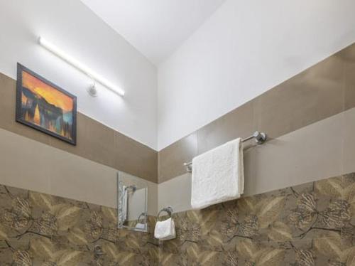 a bathroom with a painting and towels on a wall at Snowfall View Home Kasauli Operated By Splendid Hotels in Kasauli