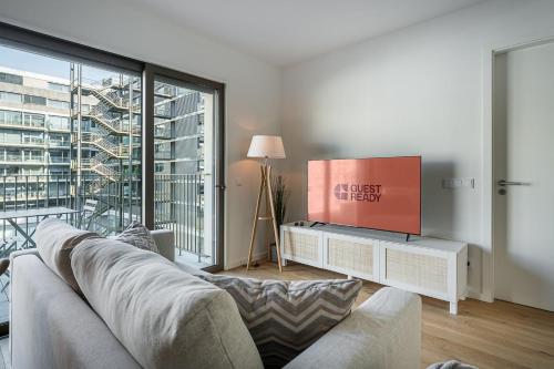Una sala de estar con un sofá y un televisor de pantalla plana. en GuestReady – Steps from Estádio do Dragão, en Oporto