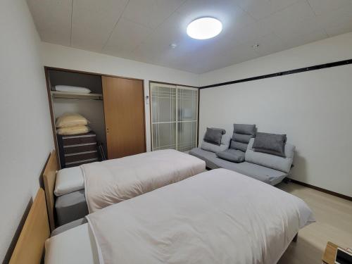a bedroom with two beds and a couch in it at ローズパーク弐番館103号室 in Funabashi
