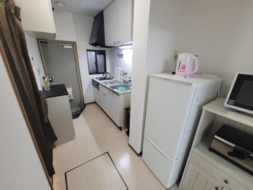 a small kitchen with a white refrigerator and a sink at ローズパーク弐番館103号室 in Funabashi