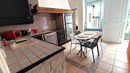 a kitchen with a sink and a table and chairs at La maison du voyageur toque in Charleville-Mézières