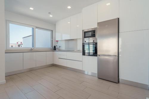 a kitchen with white cabinets and a stainless steel refrigerator at Villa Paradise 2 in Santa Barbara
