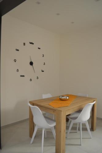 a table with chairs and a clock on a wall at Zefiro Apartment in Trapani