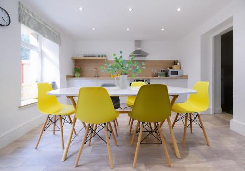 a dining room with a table and yellow chairs at 3 Bed Modern Cottage near Hiking Trails & Parks in Llwyn-y-pia