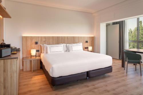 a bedroom with a large white bed and a desk at Melia Barajas in Madrid