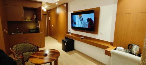 a hotel room with a television on a wall with a table at The Grace Residency - Premier , Gomtinagar , Lucknow in Lucknow