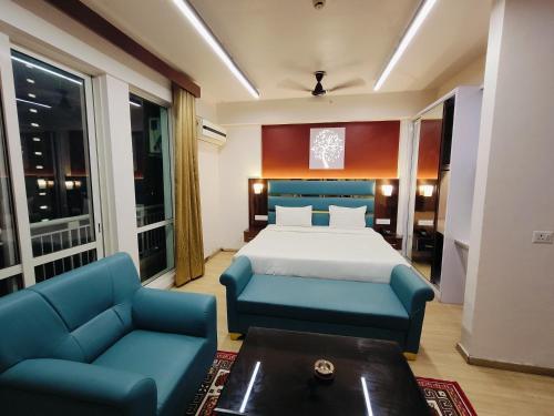 a bedroom with a bed and two blue chairs at The Grace Residency - Premier , Gomtinagar , Lucknow in Lucknow