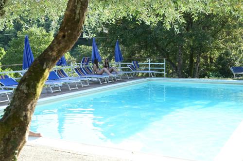 two people sitting in lawn chairs next to a swimming pool at Podere Badia Valdrago Agriturismo Mugello Circuit in Scarperia