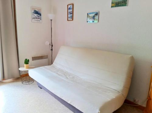 a white bed in a room with a white wall at La Parenthèse - Appartement vue sur les montagnes in Morzine