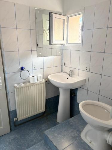 a white bathroom with a sink and a toilet at Pensiunea Flora TransFăgărășan in Cumpăna