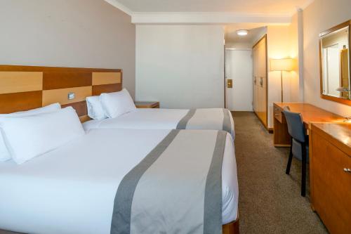 a hotel room with two beds and a desk at Grand Hotel Blackpool in Blackpool