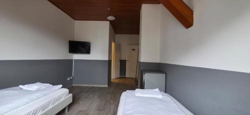 a room with two beds and a tv on the wall at My Pension 01 in Leinfelden-Echterdingen
