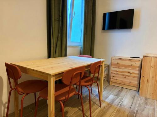 a wooden table and chairs in a room with a tv at Dragon's Den Hostel in Ħal Balzan
