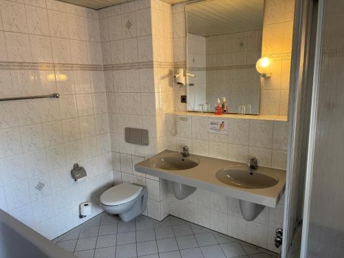 a bathroom with two sinks and a toilet at Hotel Deutsches Haus Wolfen OHG in Wolfen