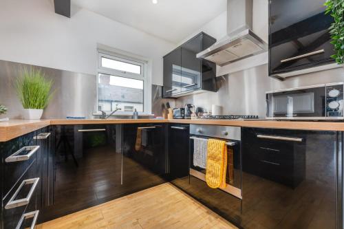 a kitchen with black cabinets and a wooden floor at Chic 2 Bedroom House in the Heart of Cardiff in Cardiff