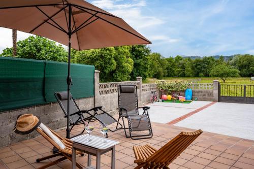 a patio with two chairs and an umbrella at Ca Carmina in Colunga