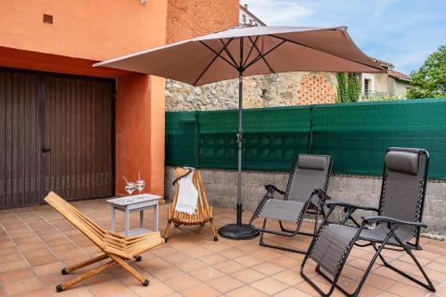 a patio with an umbrella and chairs and a table at Ca Carmina in Colunga