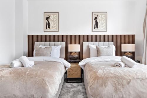 2 camas en un dormitorio con 2 lámparas en Spacious 4BR Home, Garden & Parking, Sleeps 8, en Brimsdown Station