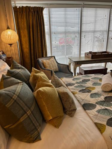 a bedroom with a bed with pillows and a chair at Rooms at number one in Broadstairs