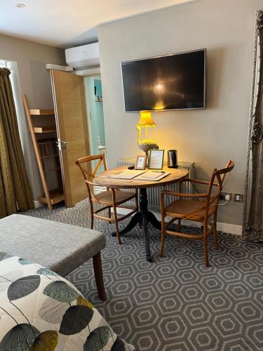 a hotel room with a table and chairs and a television at Rooms at number one in Broadstairs