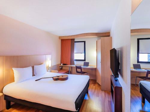 a hotel room with a large bed and a tv at Hotel Ibis Lisboa Sintra in Sintra