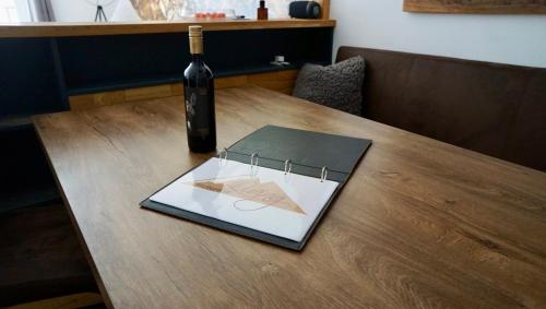 a bottle of wine and a book on a table at Runhof Living by Tirol Living in Längenfeld