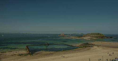 a group of people standing on a beach near the water at Hôtel La Porte Saint Pierre-Logis Hôtel Intra Muros in Saint Malo