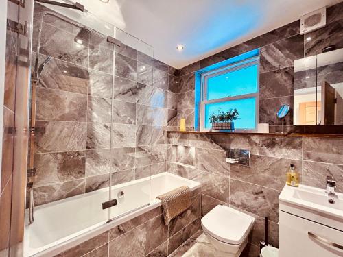 a bathroom with a tub and a toilet and a sink at Lrg Stunning 5BD CrouchEnd House in London