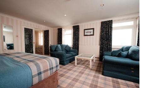 a bedroom with a bed and a couch and chairs at Lakeside Hotel and Spa in Newby Bridge