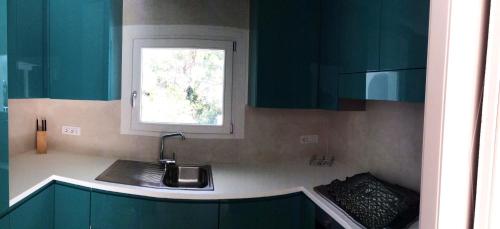 a kitchen with green cabinets and a sink and a window at Blue Eden La Maddalena in La Maddalena