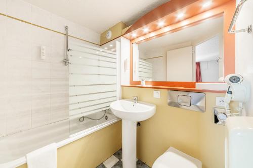a bathroom with a sink and a toilet and a mirror at Comfort Hotel Montlucon in Montluçon