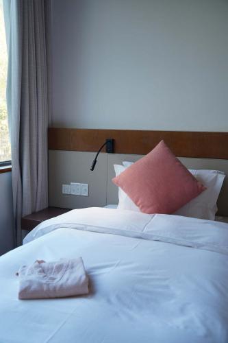 a white bed with a pink pillow on top of it at Meijie Xiuju in Xinchating