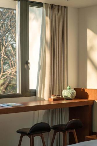 a table with two chairs and a window with a vase on it at Meijie Xiuju in Xinchating