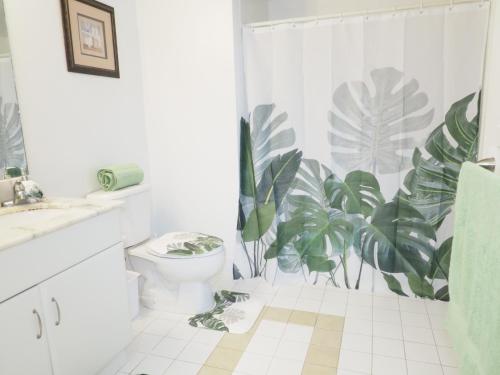 a bathroom with a toilet and a plant shower curtain at Emerald2 Room at Brighton Beach 2Min Walk to Ocean & Subway Chic Stay in Brooklyn