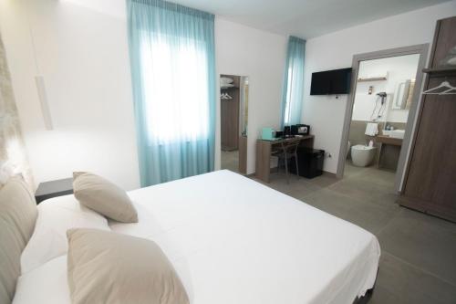 a bedroom with a white bed and a bathroom at my Vesta Suites in Vieste