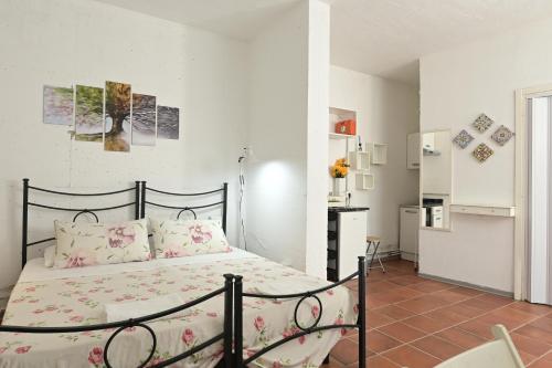 a bedroom with a bed with pink sheets and a kitchen at Podere Badia Valdrago Agriturismo Mugello Circuit in Scarperia