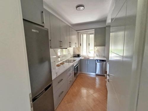 Una cocina con gabinetes blancos y un refrigerador de acero inoxidable. en NatureHouse Permet, en Përmet