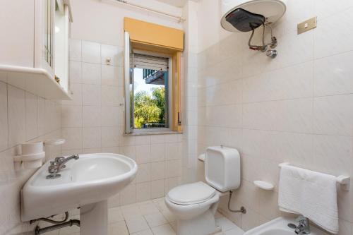 a white bathroom with a toilet and a sink at I Ciottoli Dello Ionio in Mascali