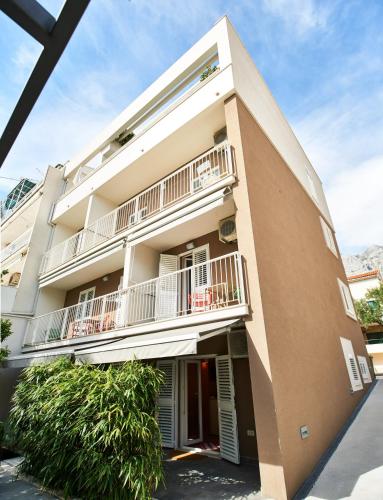 a large building with balconies and plants in front of it at Apartments House Filipović in Makarska