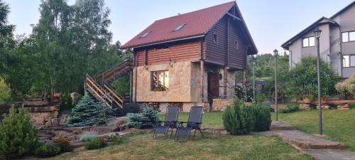 a log cabin with two chairs in a yard at Villa Zoryany Dvir in Skhidnitsa