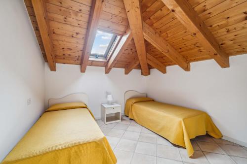 two beds in a room with wooden ceilings at Green Village Accommodations in Colico