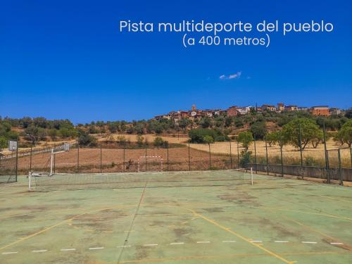an empty tennis court with a city in the background at SidroAndCo Rural Home in Secastilla