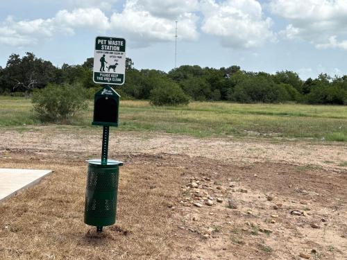 a sign on a pole with a trash can in a field at Studio 6 Giddings in Giddings