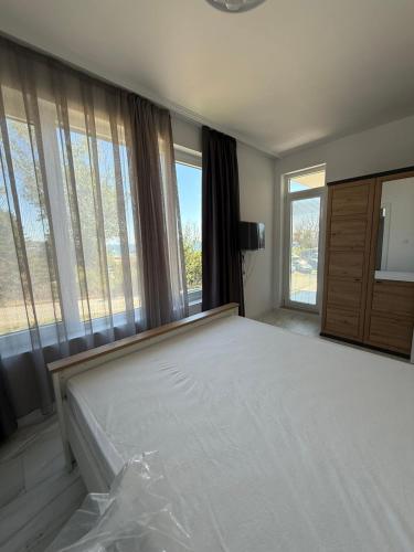 a bedroom with a large bed with windows at Aurum Villas Smokinya Beach in Sozopol
