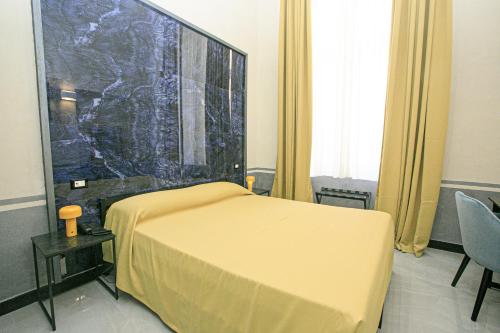 a bedroom with a yellow bed and a large wall at Hotel Torre Orefici in Genova