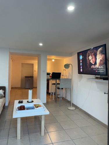 a living room with a table and a tv on the wall at Appartement cosy avec terrasse jardin in Folschviller
