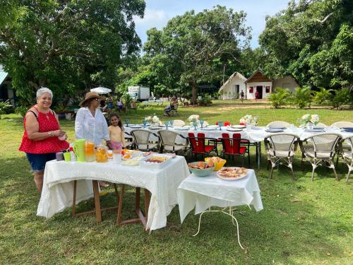 two women and a child standing at tables with food at Dreamvilles Ecovillage Las Galeras in Las Galeras