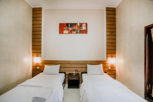 two beds in a room with a picture on the wall at Denays Guest House Jimbaran in Ngurah Rai International Airport