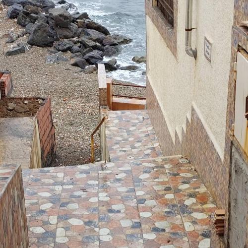 a stone walkway leading down to the beach with the ocean at Douaouda marine in Douaouda-Les Bains
